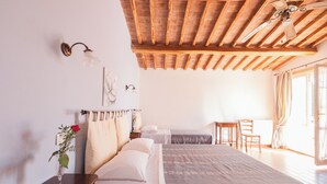 A bedroom with a wooden ceiling, a bed, a desk, and a chair. - Agriturismo La Quercia - Wine&Pool (Scansano)