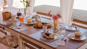 A breakfast table set with plates, cups, and a vase of flowers. - Agriturismo La Quercia - Wine&Pool (Scansano)