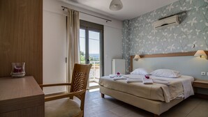 A hotel room with a bed, a desk, a chair, an air conditioning unit, and a view of the outdoors. - Villa retreat in the heart of Cretan nature (Rethimno)