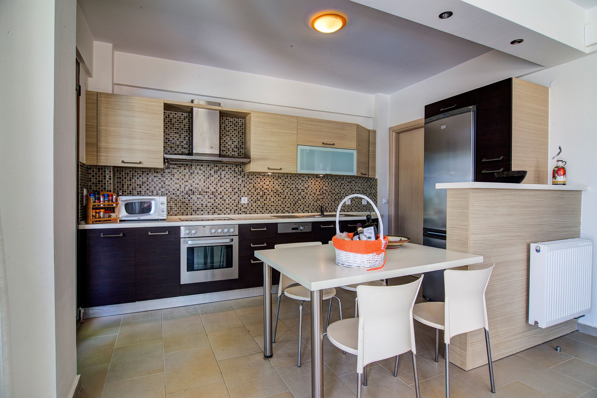 Uma cozinha moderna com área de refeições, equipada com micro-ondas, fogão, geladeira e painel de azulejos.