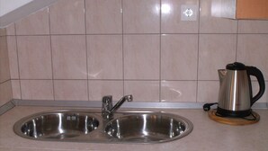 A kitchen with two stainless steel sinks, a kettle, and a tiled backsplash. - Apartment Luna (Konavle)