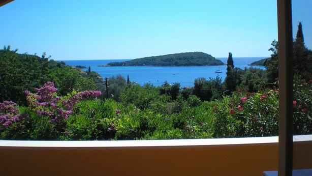 A view from a covered area overlooking a coastal landscape with a small island and a clear blue sky. - Apartment Luna (Konavle)