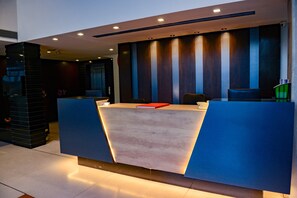 A reception desk with a modern design, featuring a light-colored countertop and blue accents. - Hotel Veronica (Vadodara)