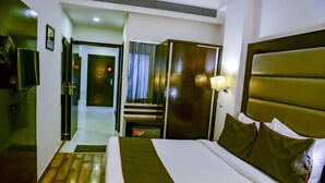 Quarto de hotel com uma cama grande, televisão, escrivaninha e espelho.