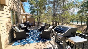 Eine Terrasse mit Gartenmöbeln, einem Grill und Blick auf Bäume sowie ein Gebäude in der Ferne.