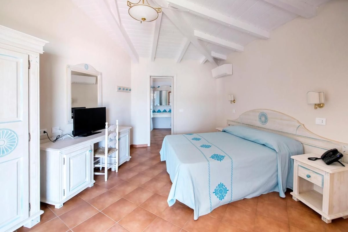 Une chambre à coucher comprenant un lit, une télévision, une armoire et une table de chevet avec un téléphone.