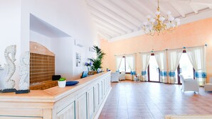 Habitación amplia con un amplio mostrador de madera, un candelabro y vistas al exterior a través de grandes ventanales con cortinas.