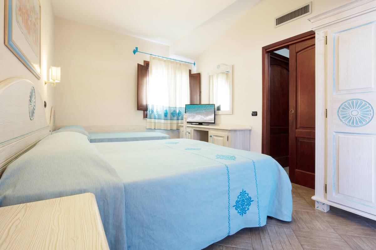 Ein Hotelzimmer mit zwei Betten, einem Fernseher, einem Kleiderschrank und einem Badezimmer.