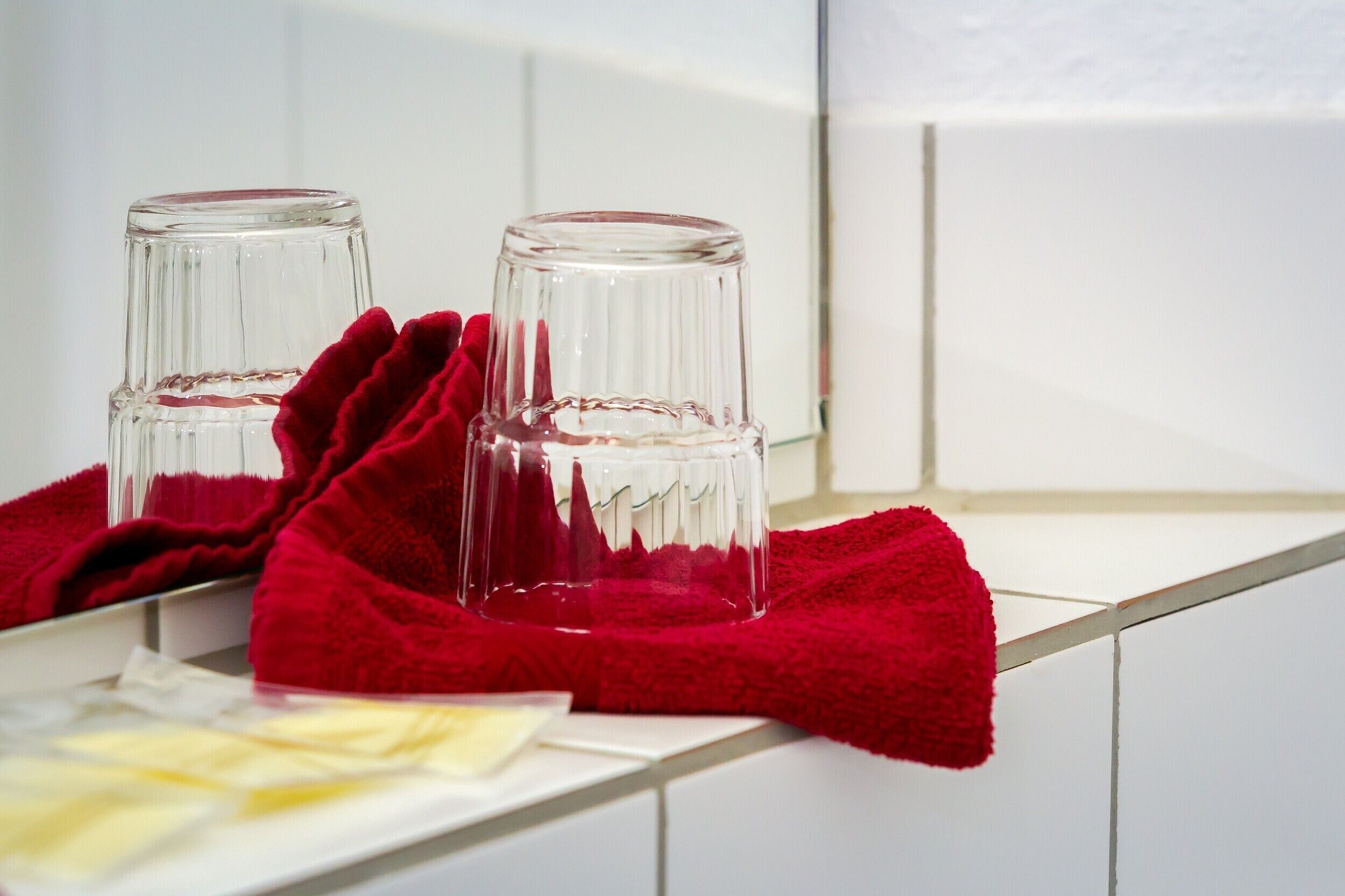 Two glass bottles on a white shelf with a red cloth.