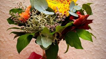 A bouquet of flowers in a clear glass vase on a wooden surface with a red cloth underneath.