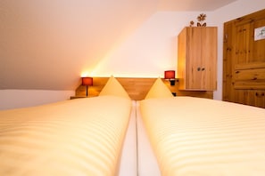 Una habitación con dos camas, armarios de madera y lámparas fijadas a la pared.