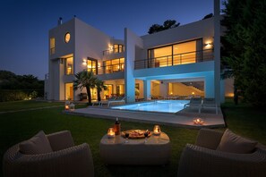 Uma casa moderna com dois andares, piscina, área de estar externa e um pátio.