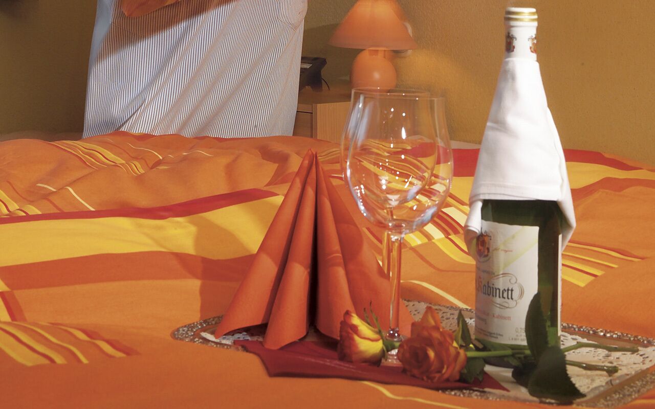 Una mesa ordenada con una botella de vino, una copa y un mantel doblado.