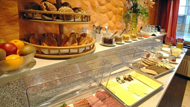 A buffet with various food items including bread, fruits, and meats.
