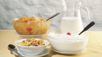 A table with three bowls of food and a pitcher of milk.