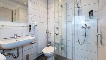 A modern bathroom with a glass shower enclosure, a white sink, and a toilet.