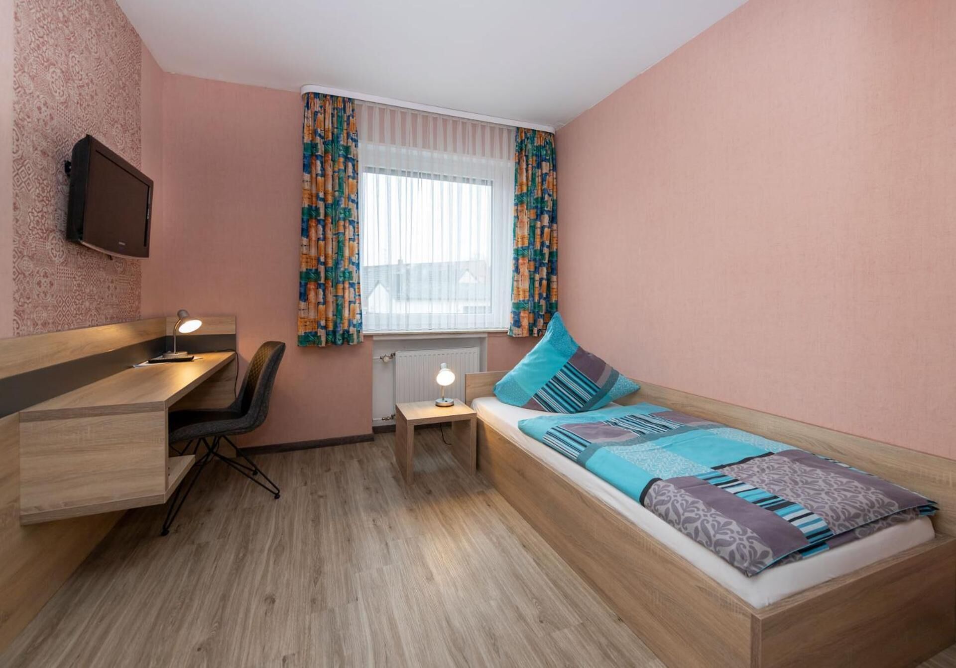Ein kleines Zimmer mit einem Bett, einem Schreibtisch und einem Stuhl.