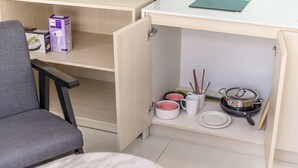 A compact kitchen with a wooden cabinet, a chair, and a table. - Sumi Home (Da Nang)