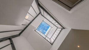 A high ceiling with a skylight and a metal staircase. - Sumi Home (Da Nang)