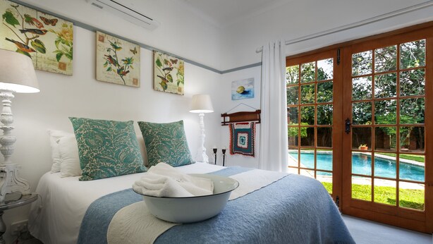 Een slaapkamer met een groot bed, een handdoekenset en uitzicht op een zwembad door een glazen deur.