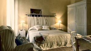 A bedroom with a bed, two bedside tables, a chair, a wardrobe, and a shelf with books. - CASA DARIO APARTMENT 5 (Castellina in Chianti (SI), Italia)