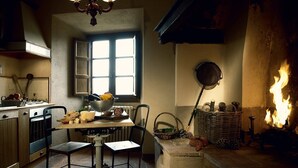 A cozy kitchen with a dining table, chairs, a window, and a fireplace. - CASA DARIO APARTMENT 5 (Castellina in Chianti (SI), Italia)