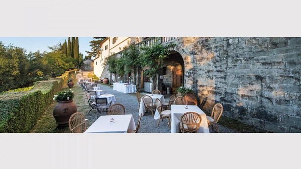 An outdoor dining area with tables and chairs, a stone wall, and greenery. - CASA DARIO APARTMENT 5 (Castellina in Chianti (SI), Italia)
