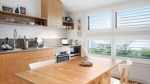 Une cuisine moderne avec des meubles en bois, une table à manger et une vue sur la verdure environnante.