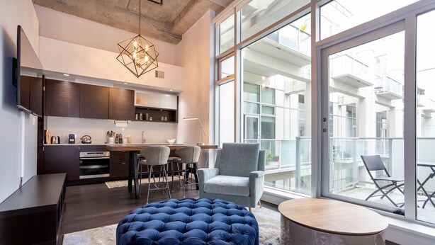 A modern kitchen with dark wood cabinets, a dining area with a round table, and a large window overlooking a balcony. - Hudson Hideaway-Historic Hudson Building in Beautiful Downtown Victoria by Victoria Prime! (Victoria)