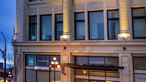 A historic building with large columns, a ground-floor entrance, and a sign for 'Hudson' on the facade. - Hudson Hideaway-Historic Hudson Building in Beautiful Downtown Victoria by Victoria Prime! (Victoria)
