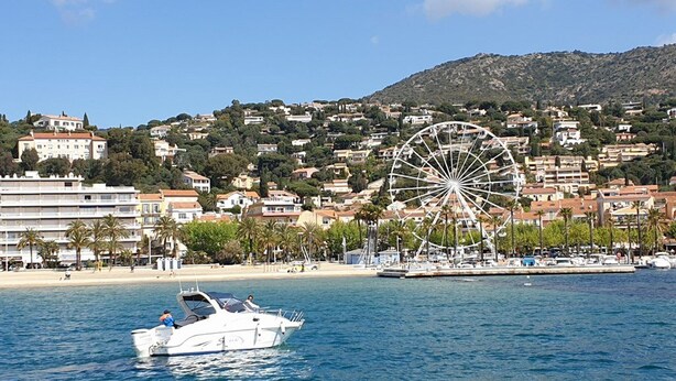 Eine Küstenstadt mit einem markanten Riesenrad, einem Strand und einem Boot auf dem Wasser.