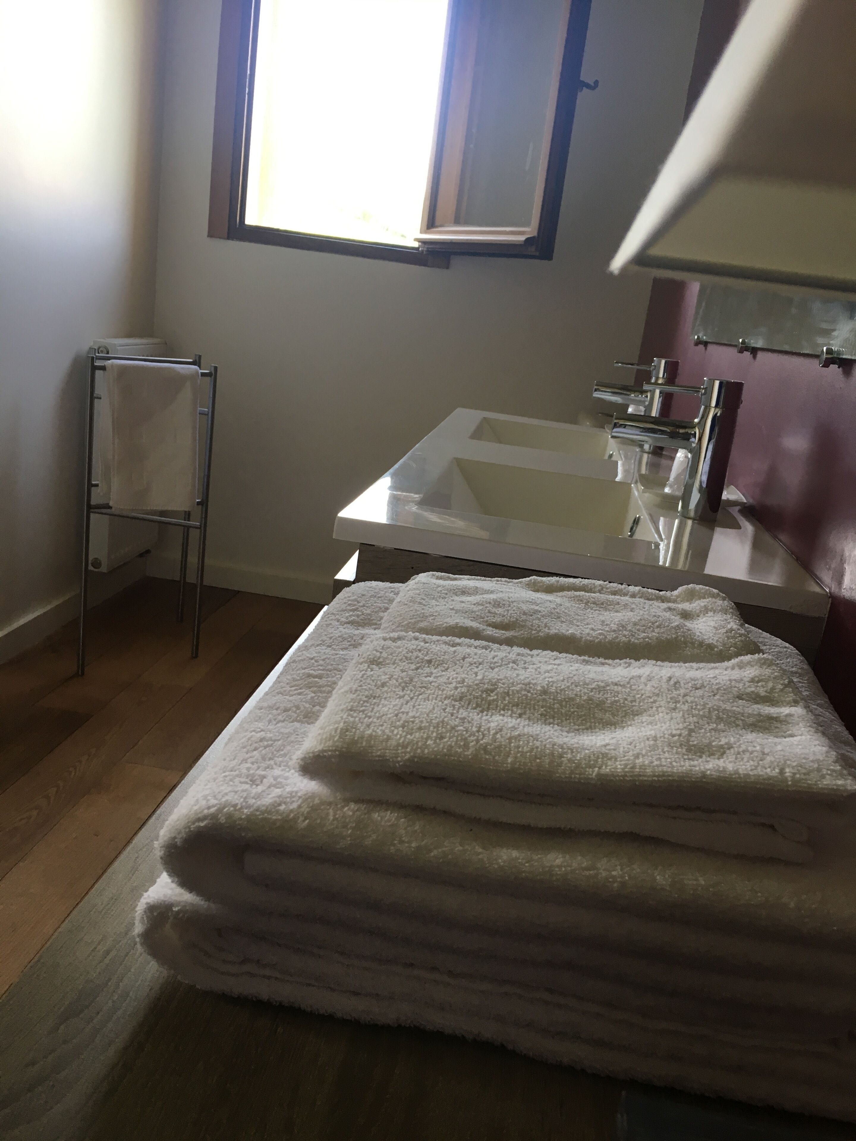 Un baño con lavamanos blanco, toallero y ventana.