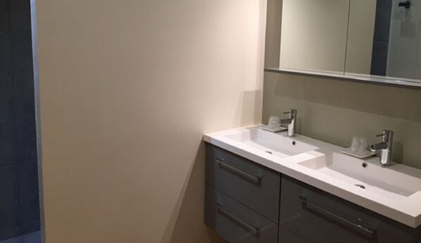 Un baño con dos lavamanos, un espejo y un mueble con cajones.