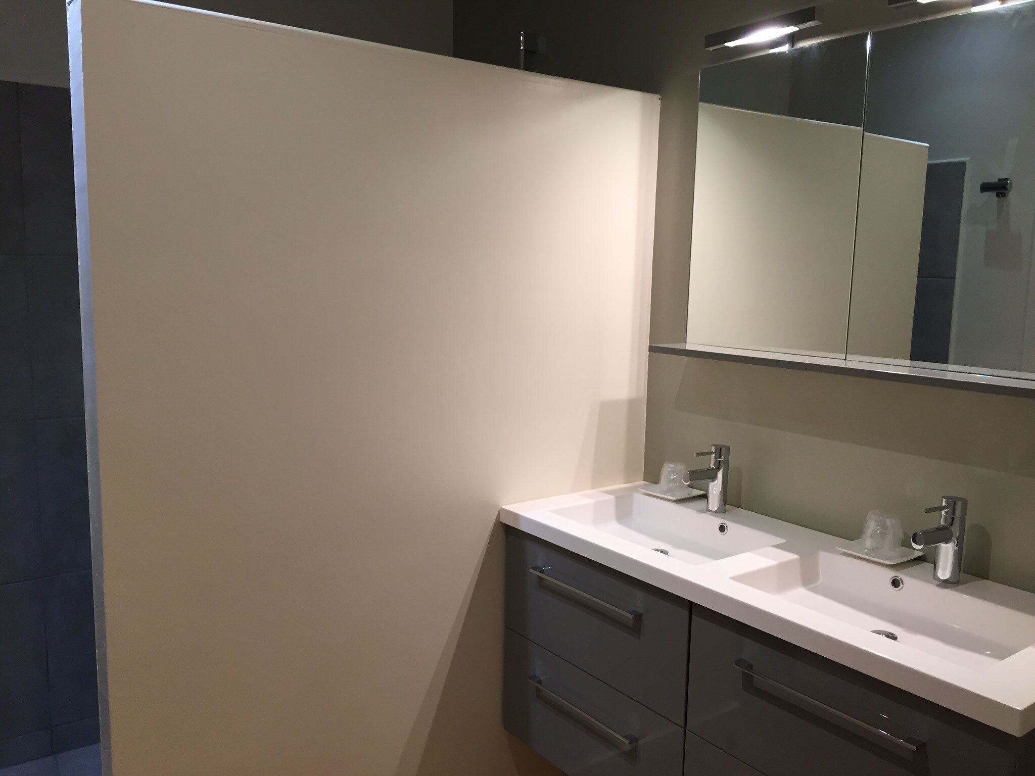 Un baño moderno con dos lavamanos, un espejo grande y un mueble con cajones.