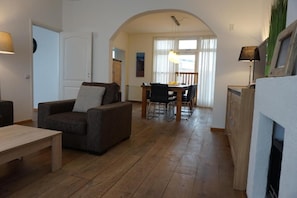A living room with a sofa, a dining table with chairs, and a kitchen area with a counter and cabinets.