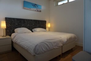 A bedroom with a bed, two bedside tables, and two lamps.