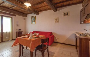 A dining area with a table set for two, a red sofa, and a kitchen area with a sink and cabinets.