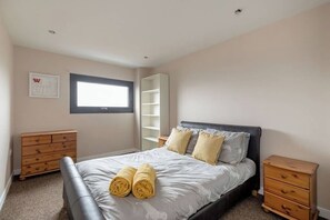 Une chambre à coucher avec un lit, deux tables de chevet, une armoire et une fenêtre.