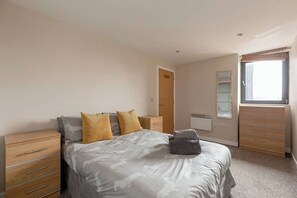 A bedroom with a bed, a dresser, a mirror, and a window. - Close to Hydro/SECC: Modern Riverside Apt with Parking (Glasgow City)
