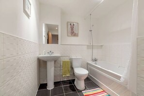A bathroom with a sink, toilet, bathtub, and a mirror. - Close to Hydro/SECC: Modern Riverside Apt with Parking (Glasgow City)