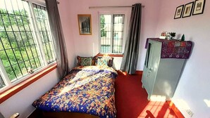 A bedroom with a bed, a desk, a wardrobe, and a window with curtains. - A Dutch Nepali home with a beautiful view (kathmandu)
