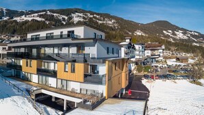 A modern multi-story building with large windows and balconies, located in a snowy mountainous area. - Residenz Schiestl (Fuegenberg)