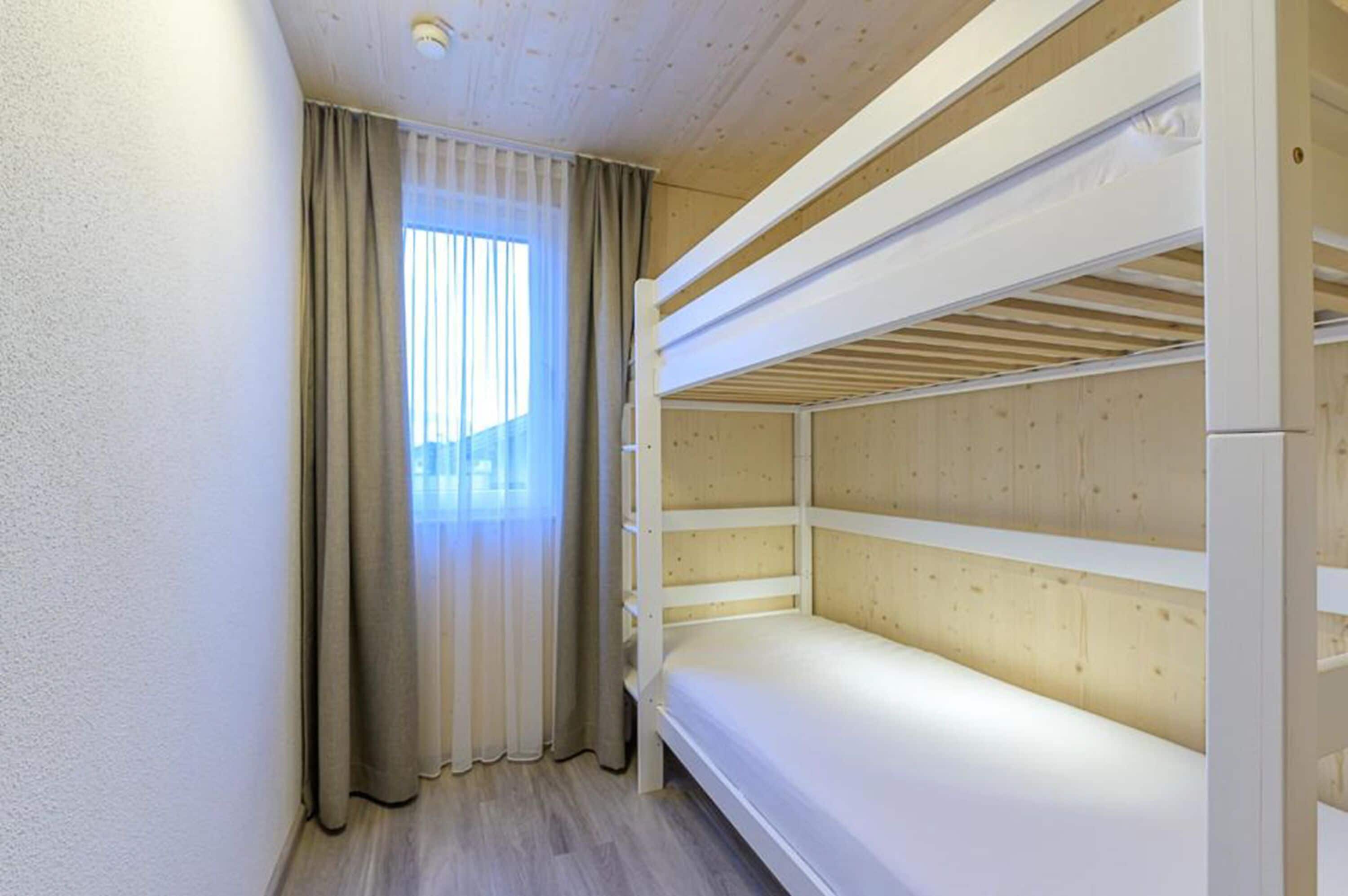 A bunk bed room with a window and curtains.