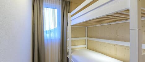 A bunk bed room with a window and curtains.