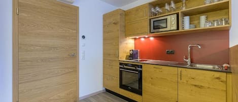 A compact kitchen with wooden cabinets, a microwave, a sink, and a built-in oven.