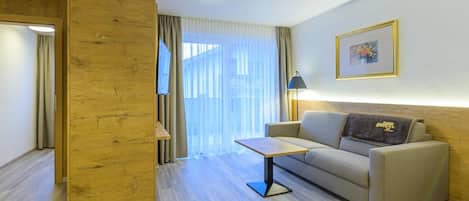 Ein modernes Hotelzimmer mit einer Holzwand, einer Couch, einem kleinen Tisch und einer Lampe.