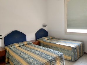 A room with two beds, each with a headboard and a patterned bedspread. There is a nightstand with a lamp between the beds. - Hotel Riverside (San Cesario sul Panaro)