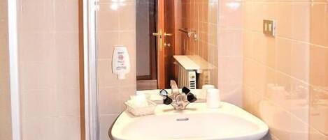 A bathroom with a sink, mirror, and a trash bin.