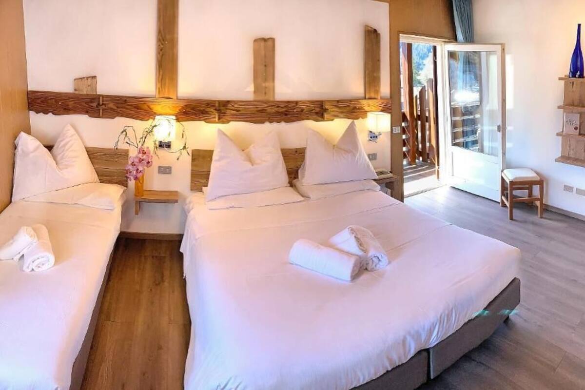 Een hotelkamer met twee bedden, houten hoofdeinden, een tafeltje en een stoel.