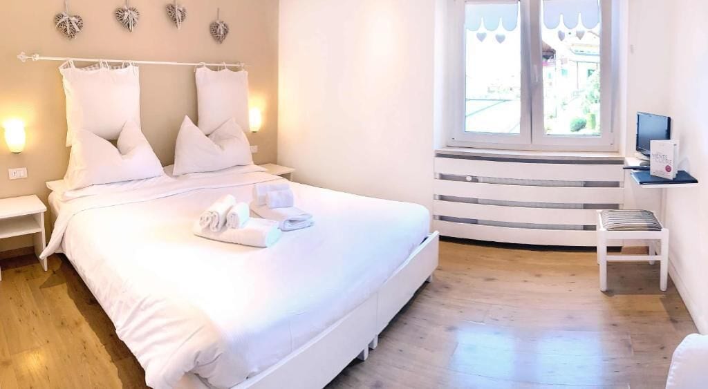 A neatly arranged bedroom with a large bed, bedside tables, and a window with a view.